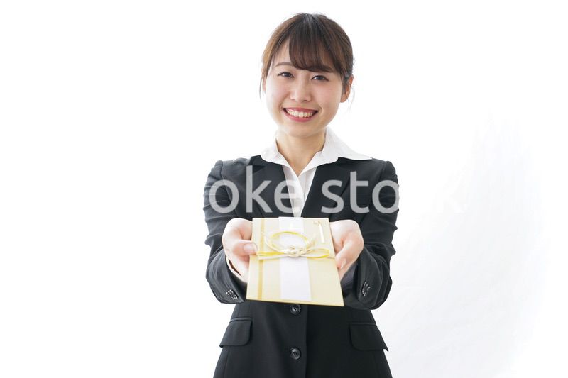 祝儀袋を渡すスーツ姿の女性