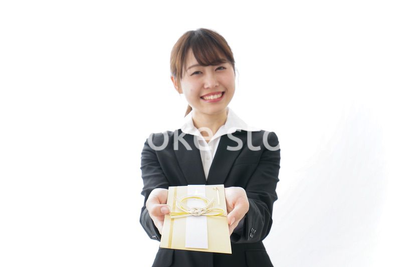 祝儀袋を渡すスーツ姿の女性