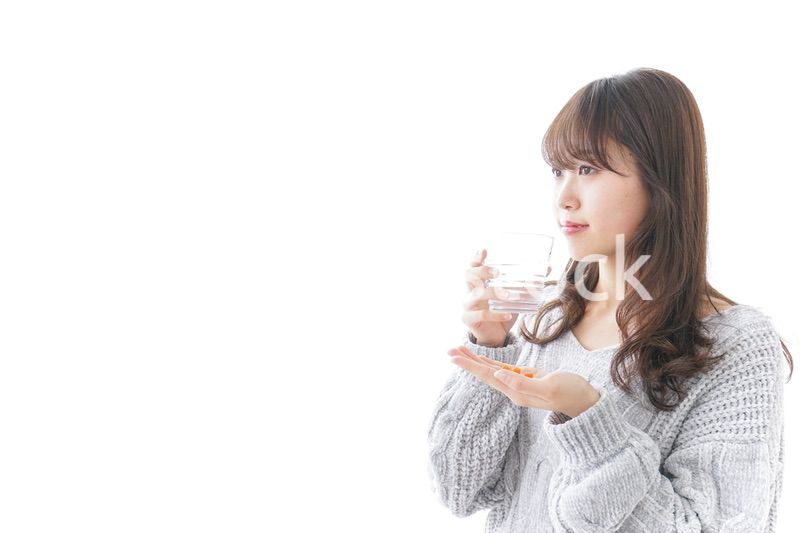 錠剤・サプリメントを飲む女性