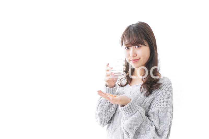 錠剤・サプリメントを飲む女性