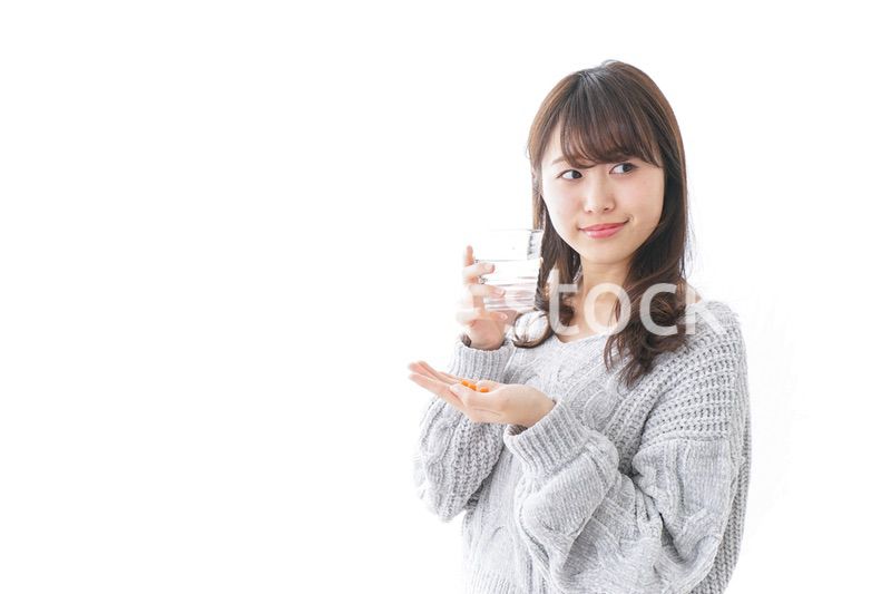 錠剤・サプリメントを飲む女性