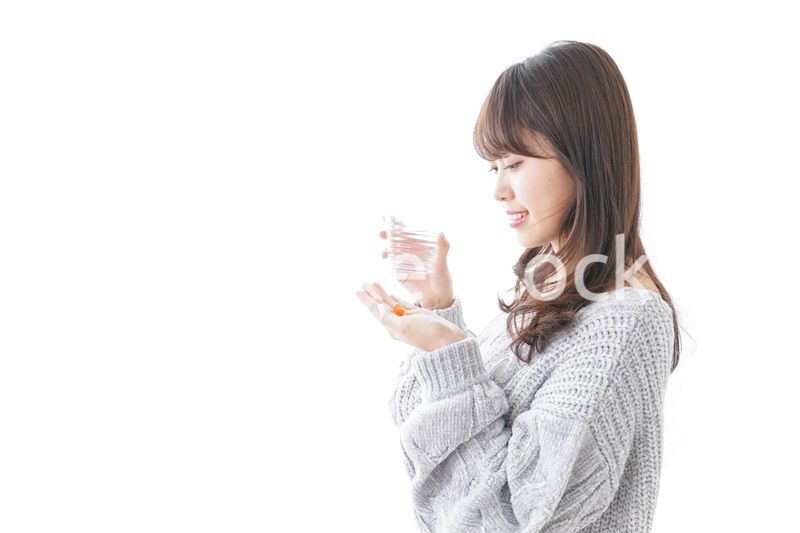 錠剤・サプリメントを飲む女性