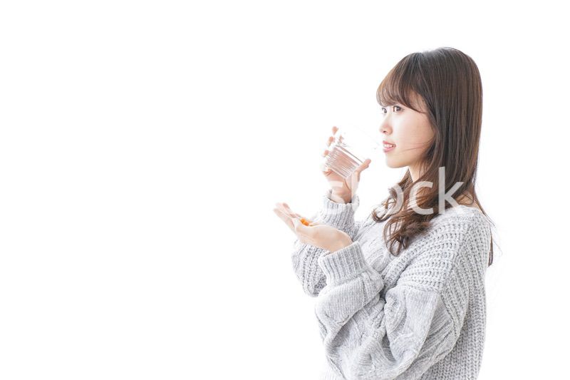 錠剤・サプリメントを飲む女性
