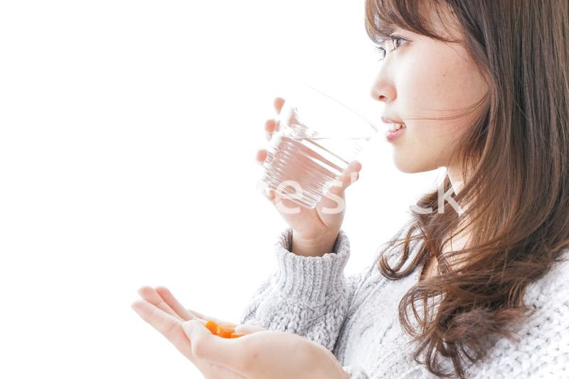錠剤・サプリメントを飲む女性