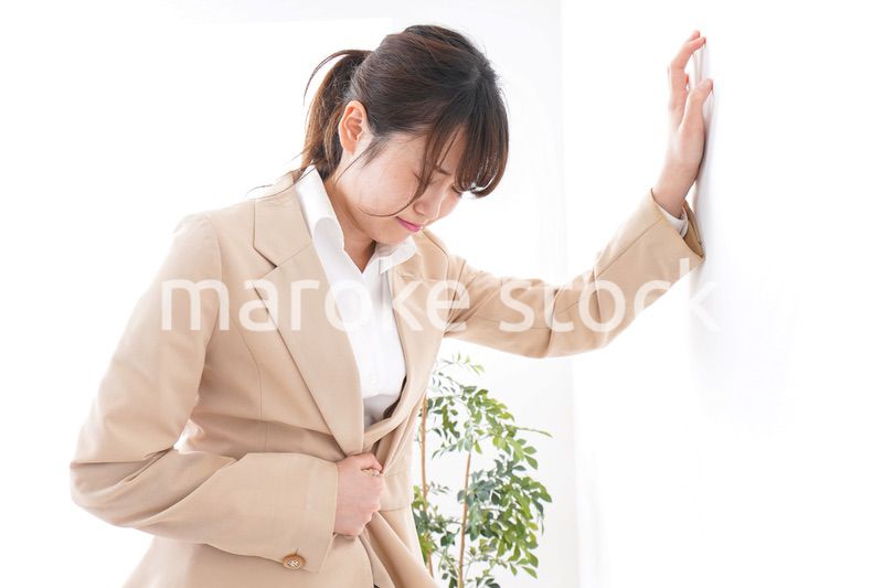 腹痛で苦しむビジネスウーマン