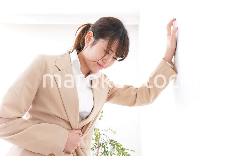 腹痛で苦しむビジネスウーマン