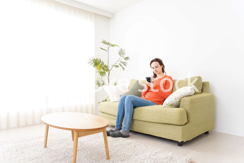 家でスマホを使う若い女性