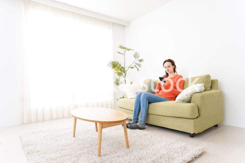 家でスマホを使う若い女性