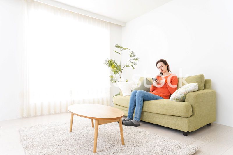 家でスマホを使う若い女性