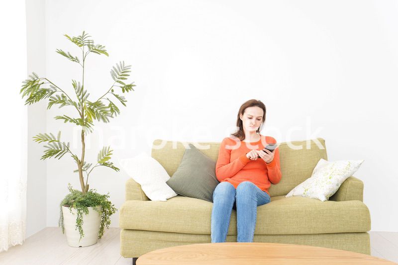 家でスマホを使う若い女性