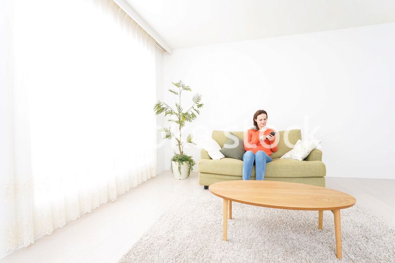 家でスマホを使う若い女性