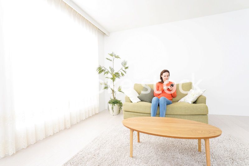 家でスマホを使う若い女性