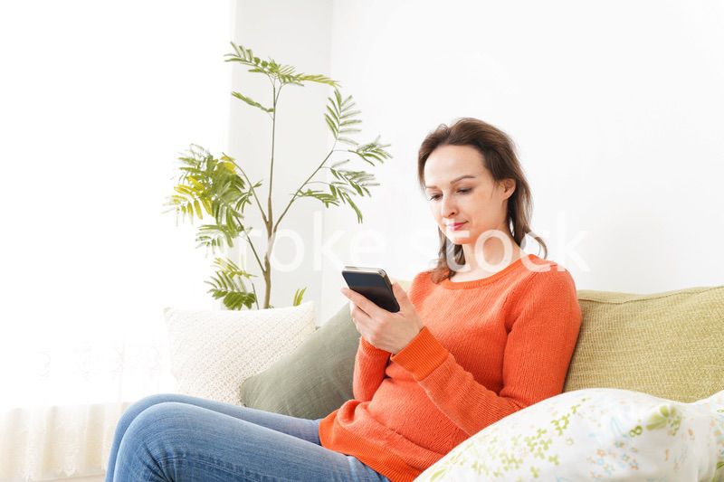 家でスマホを使う若い女性