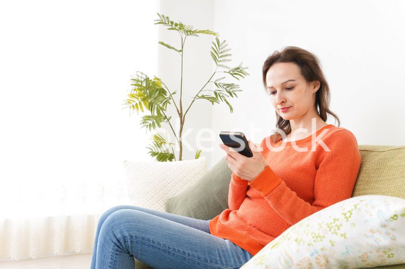 家でスマホを使う若い女性