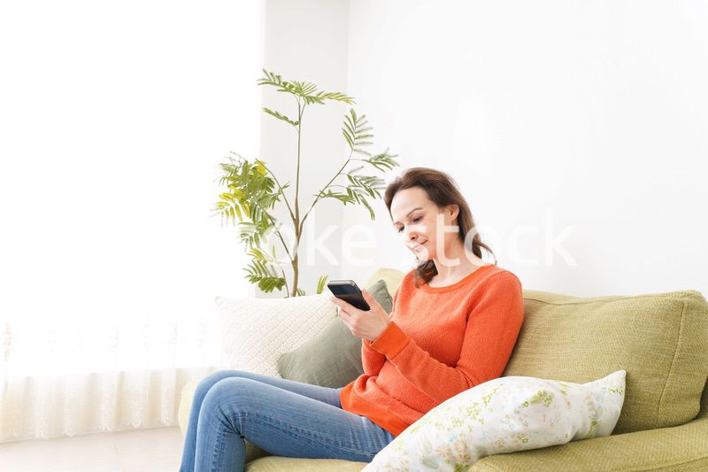 家でスマホを使う若い女性