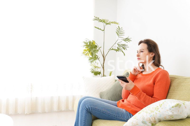 家でスマホを使う若い女性