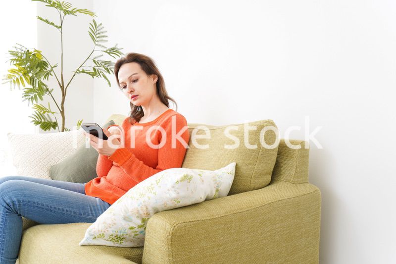 家でスマホを使う若い女性