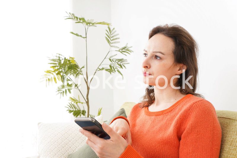 家でスマホを使う若い女性