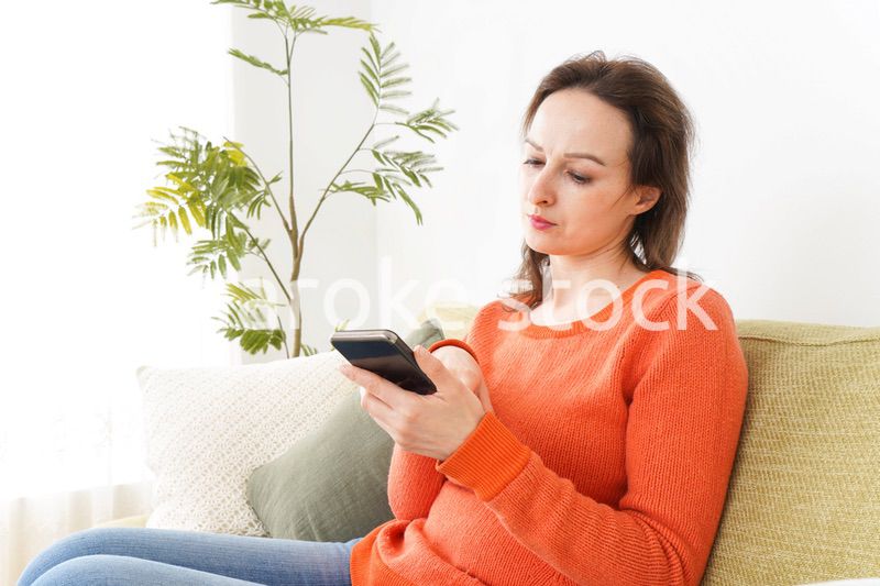 家でスマホを使う若い女性