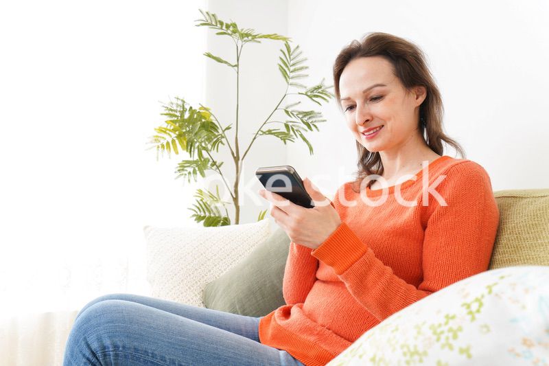 家でスマホを使う若い女性