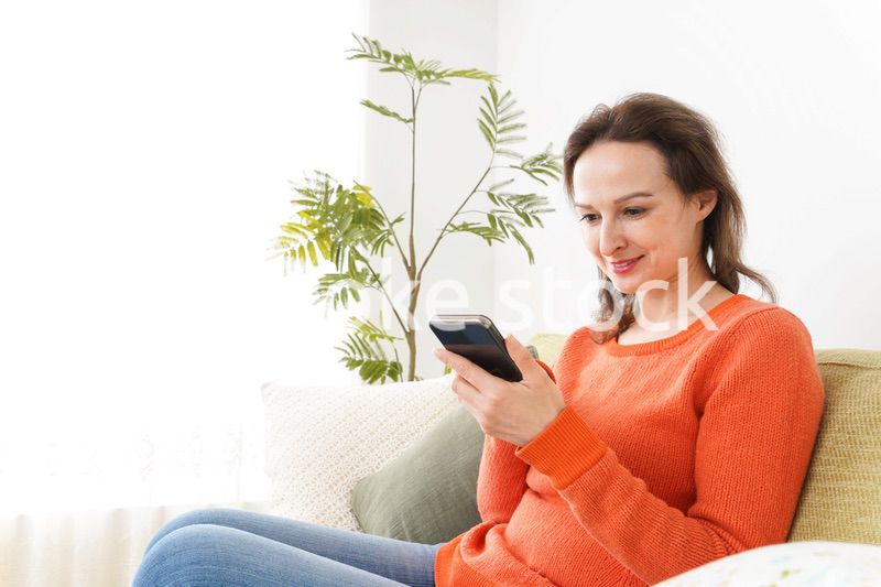 家でスマホを使う若い女性