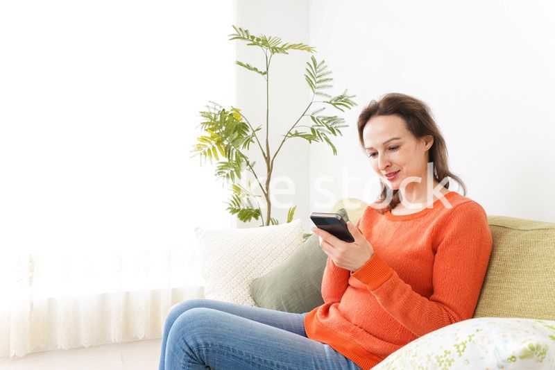 家でスマホを使う若い女性