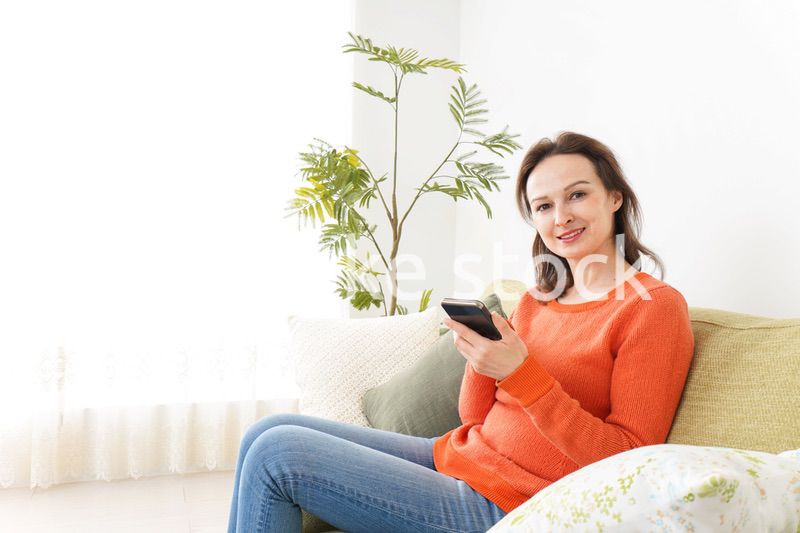 家でスマホを使う若い女性