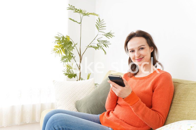 家でスマホを使う若い女性