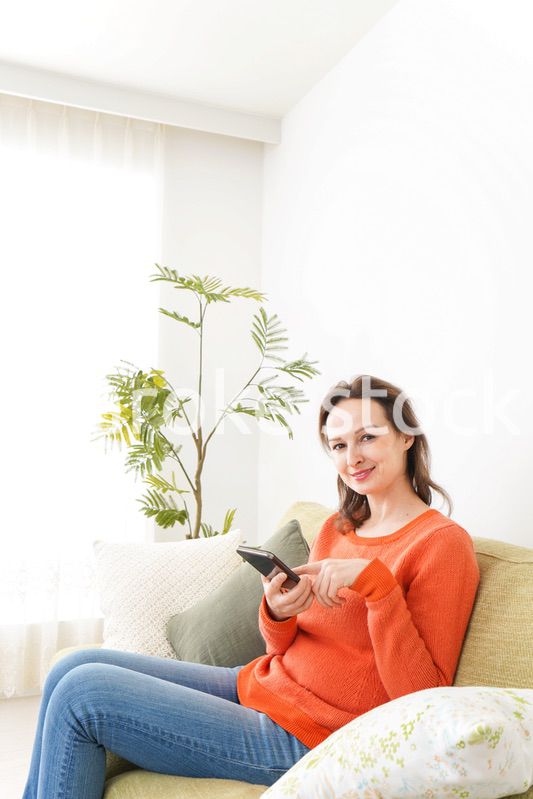 家でスマホを使う若い女性