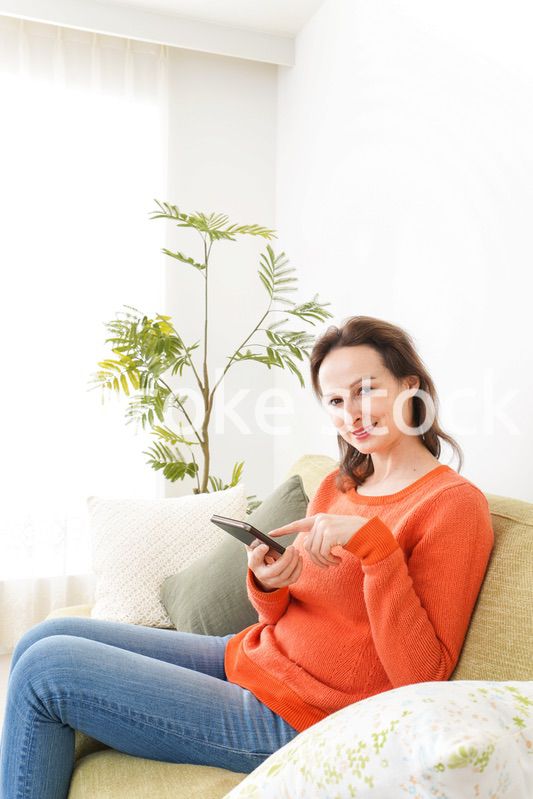 家でスマホを使う若い女性