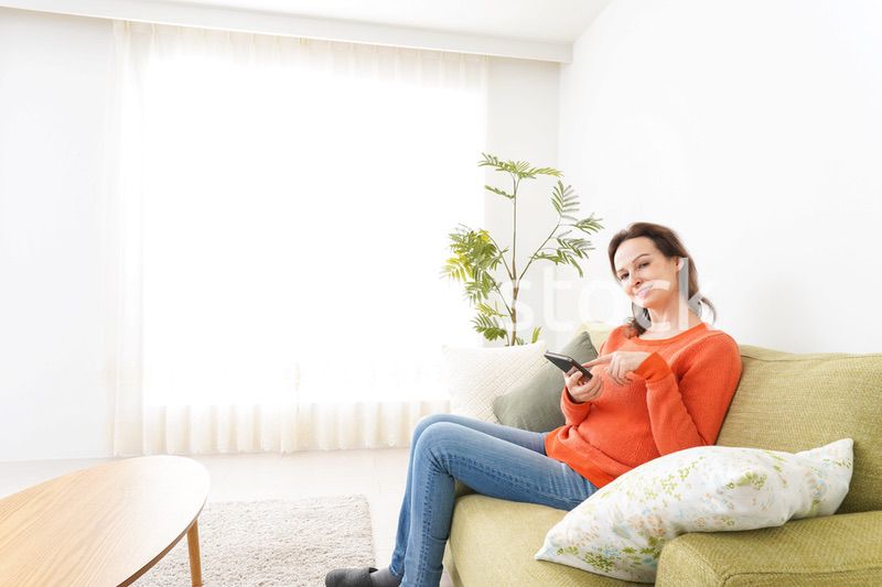 家でスマホを使う若い女性