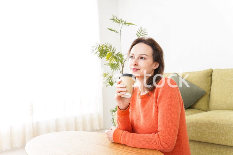 家でコーヒーを飲む若い女性
