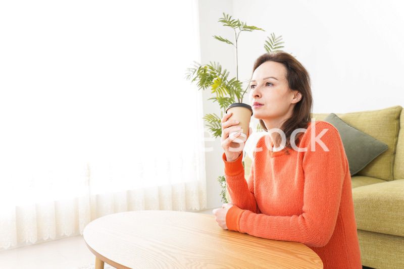 家でコーヒーを飲む若い女性