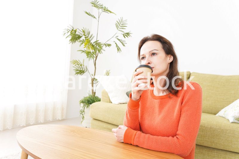 家でコーヒーを飲む若い女性