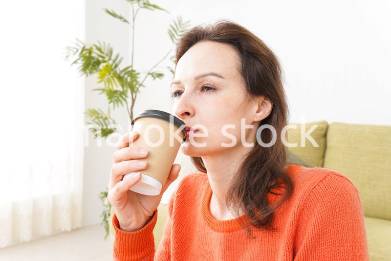 家でコーヒーを飲む若い女性