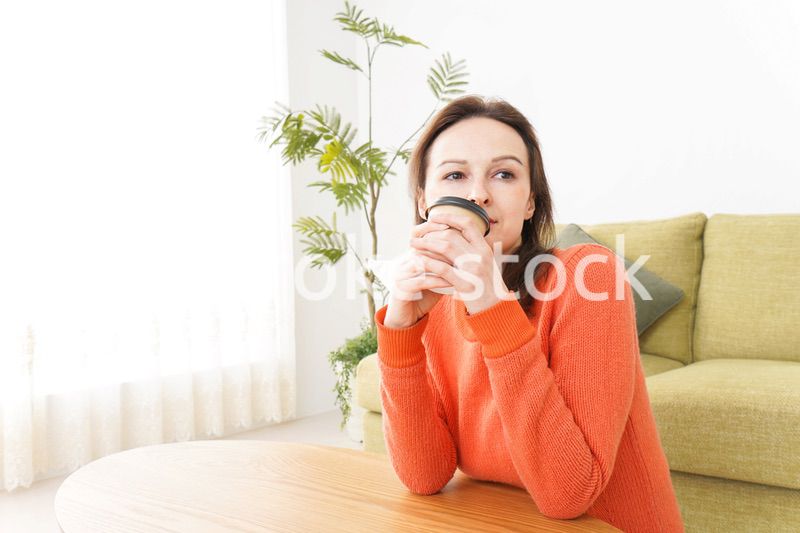 家でコーヒーを飲む若い女性