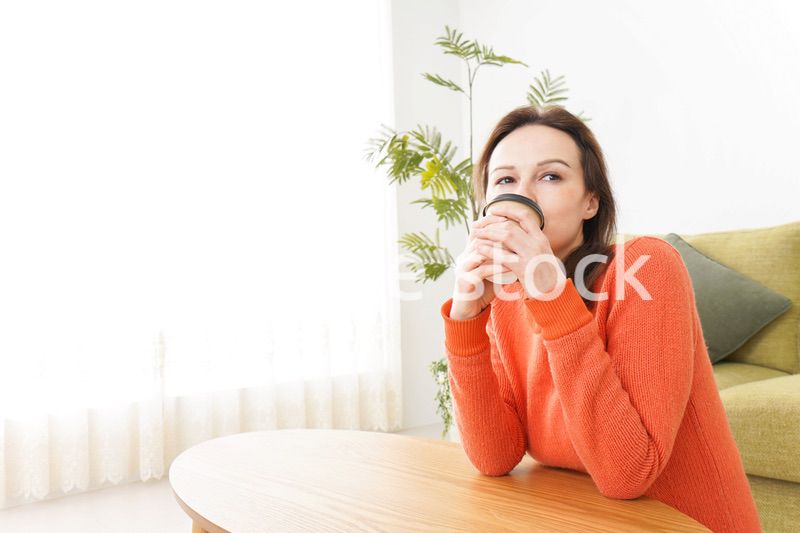 家でコーヒーを飲む若い女性