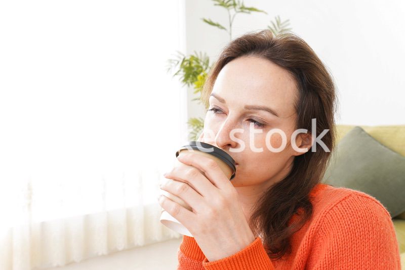 家でコーヒーを飲む若い女性