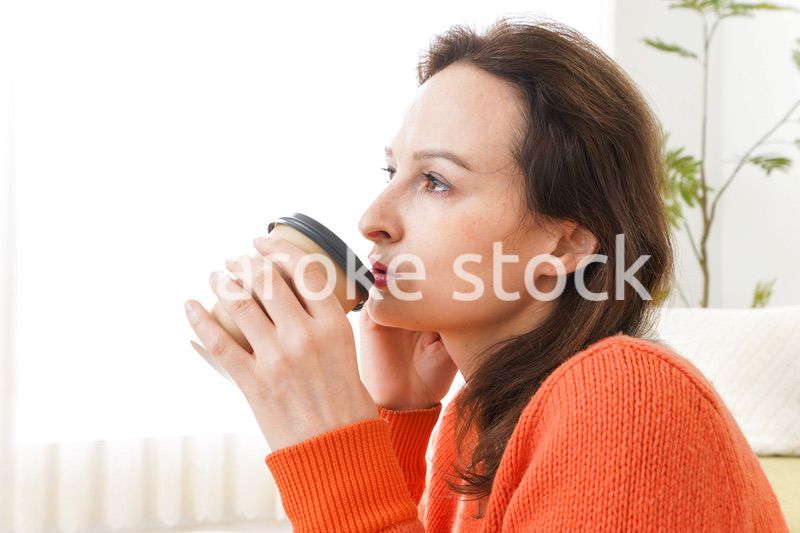 家でコーヒーを飲む若い女性