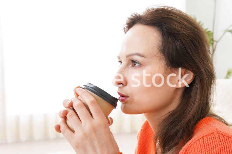 家でコーヒーを飲む若い女性