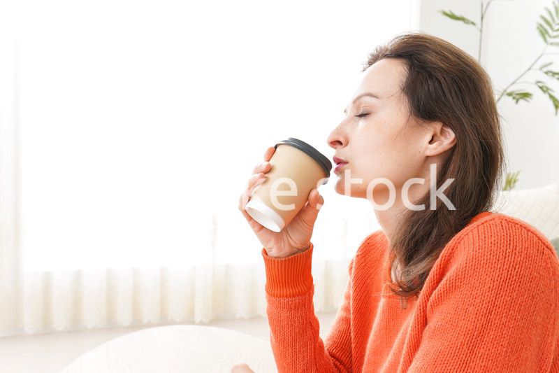 家でコーヒーを飲む若い女性