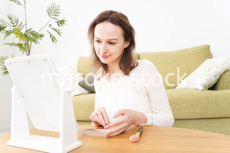 自宅で化粧をする若い女性
