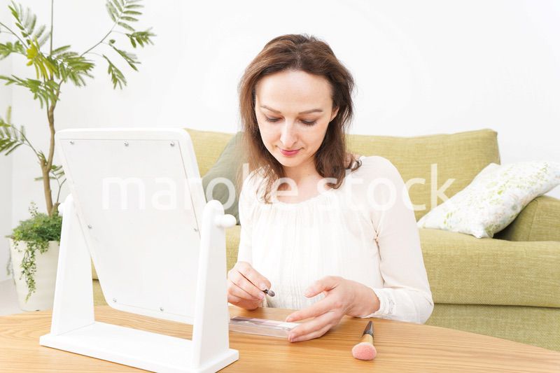 自宅で化粧をする若い女性