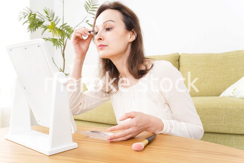 自宅で化粧をする若い女性