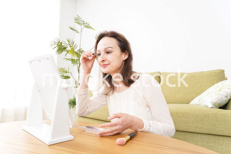 自宅で化粧をする若い女性