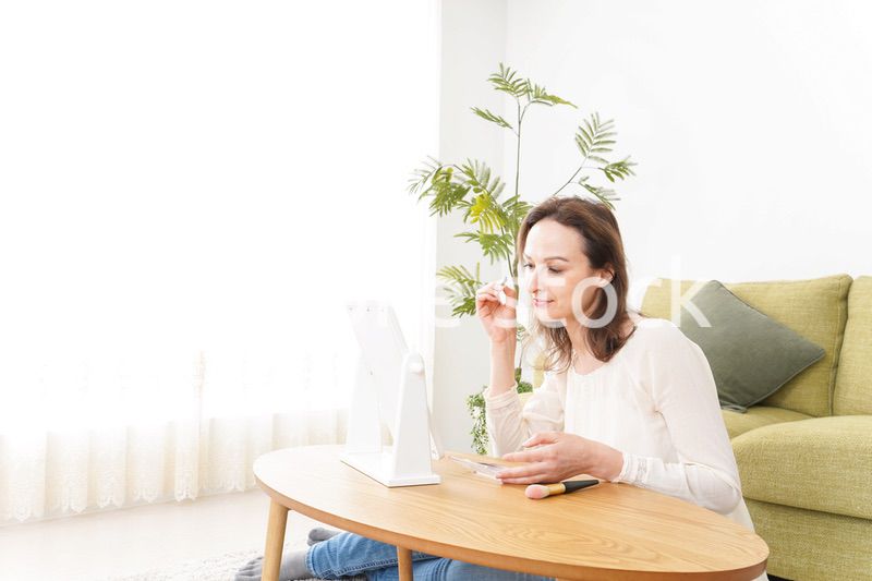 自宅で化粧をする若い女性