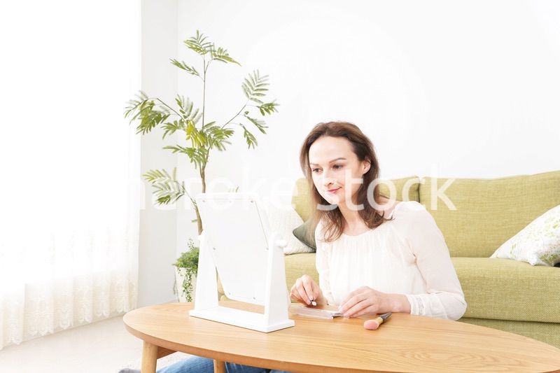 自宅で化粧をする若い女性