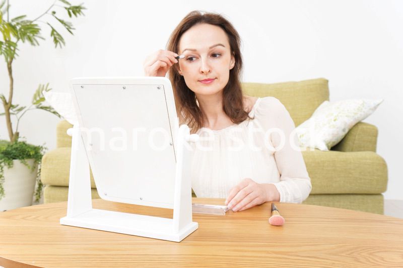 自宅で化粧をする若い女性