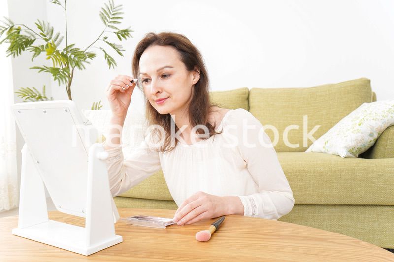 自宅で化粧をする若い女性