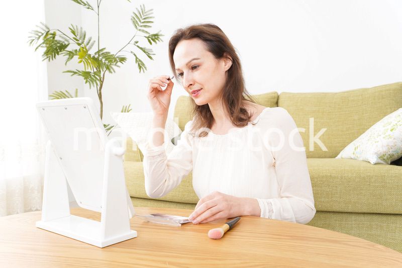 自宅で化粧をする若い女性